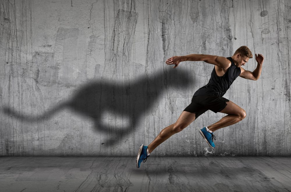 Strong athletic man sprinter, running on dark wall background wearing in sportswear. Sport and fitness motivation